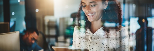 A woman smiles while viewing a laptop